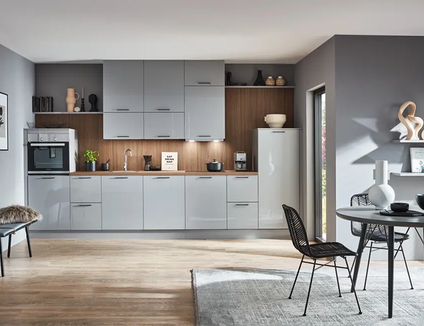 Helle moderne Küche mit weißen Hochglanzfronten, einer hellen Arbeitsplatte und schwarzem Esszimmertisch mit passenden Stühlen.