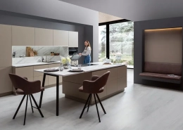 Moderne Küche mit hellen Fronten und heller Arbeitsplatte aus Marmor, die Kücheninsel geht direkt in einen Tresen über.