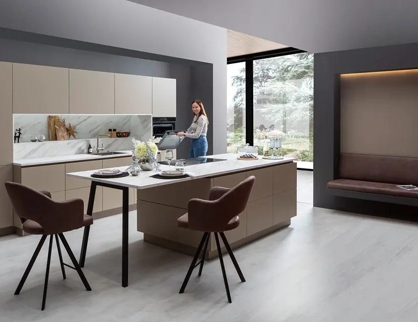 Moderne Küche mit hellen Fronten und heller Arbeitsplatte aus Marmor, die Kücheninsel geht direkt in einen Tresen über.